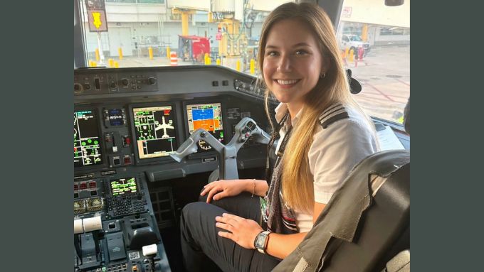 Young Caucasion woman wearing a pilot uniform in the cockpit of an airplane