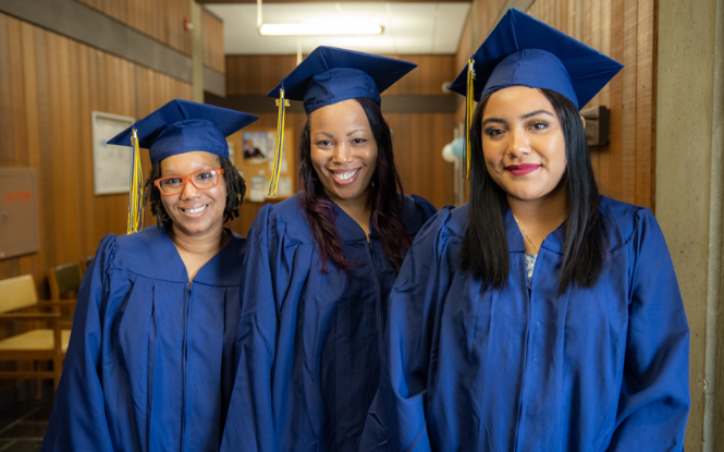 three female WEI graduates wearing cap and gown