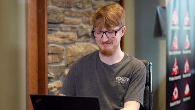 White male wearing glasses and viewing his laptop