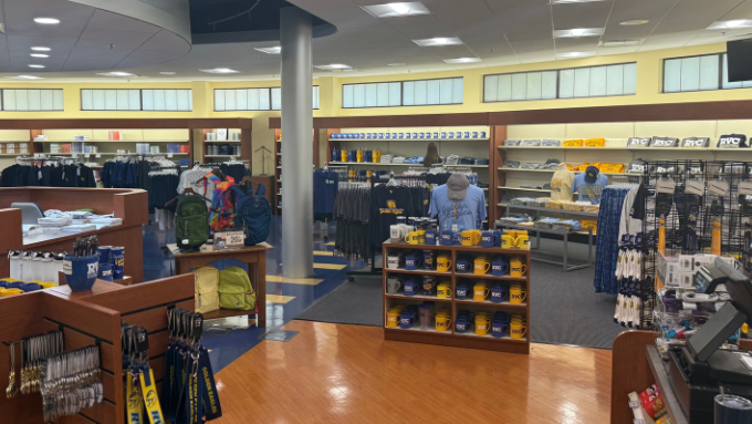 A photo of bookstore on campus with mugs and hats in the foreground
