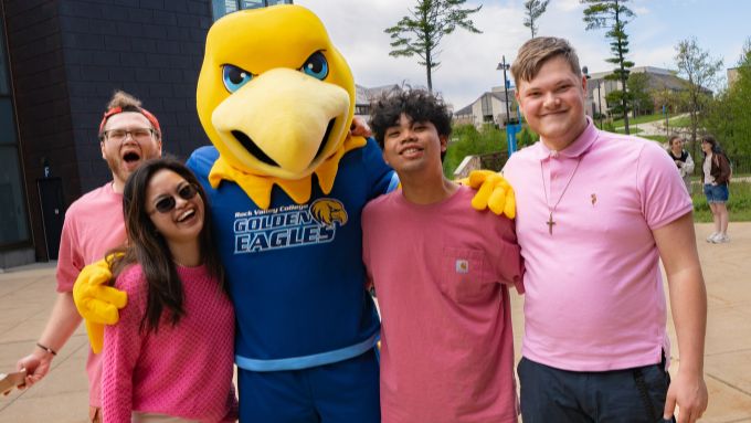 Two Caucasian males, one Asian female and one African American male with RVC mascot