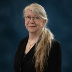 portrait of an older white woman with long blonde hair and glasses