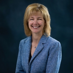 portrait of an older white woman with shoulder length dark blonder hair and a blue suit
