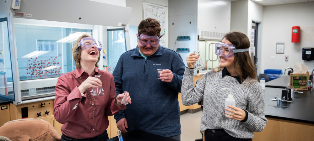 three students in science lab doing experiment