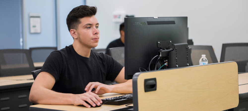 male student in black shirt sitting at computer