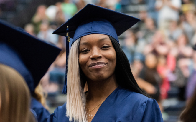 adult education graduate at ceremony wearing blue cap and gown