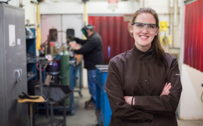 female student with safety glasses standing in welding lab